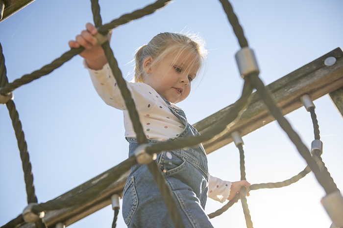 Buiten spelen Little girl being brave climbing through a adventure playground in public park
