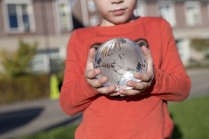 Toekomst Child holding a glass globe in a public park, reflective light and clear glass