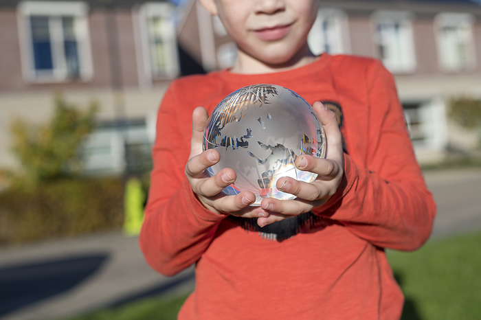 Toekomst Child holding a glass globe in a public park, reflective light and clear glass
