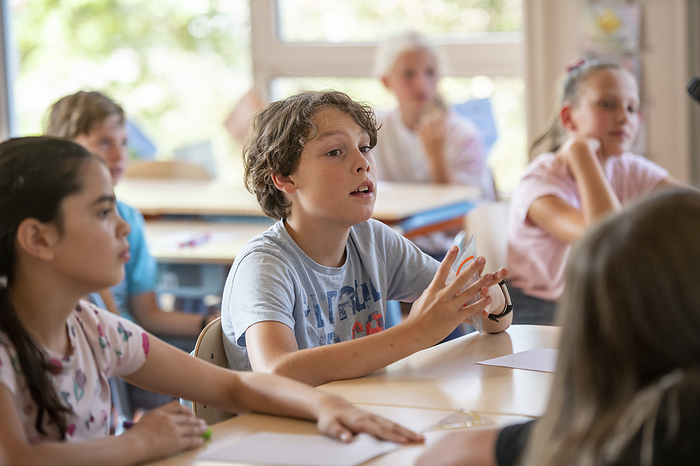 Basisonderwijs Young boy in class answering the teachers questions