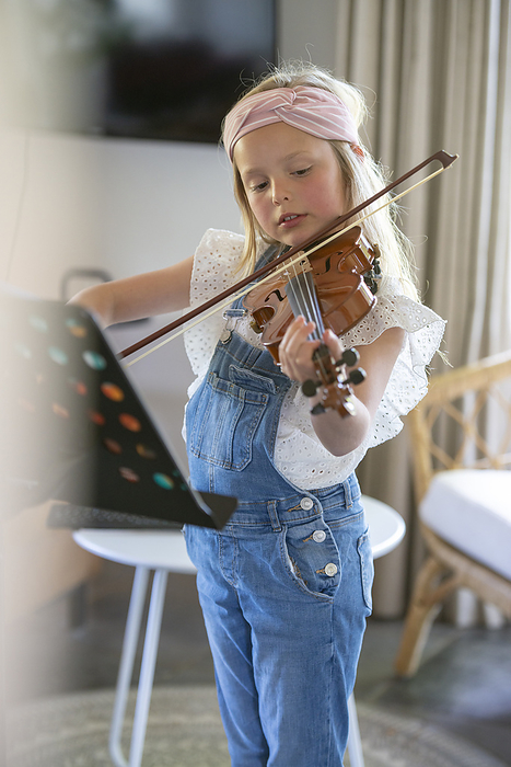 meisje oefent op haar viool Young girl practising her violin with her new music stand.