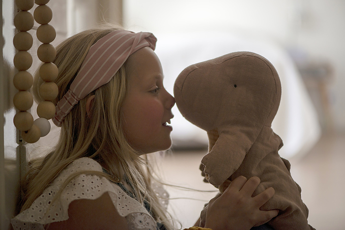 meisje praat met knuffel Young girl sitting in her hallway hugging her teddy. Comforted by the soft toy