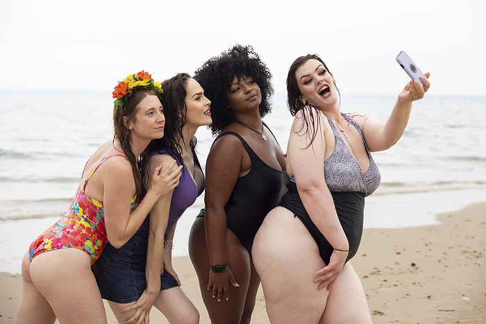 A mixed group of female friends having fun at the beach. A mixed group of female friends having fun at the beach taking a selfie.