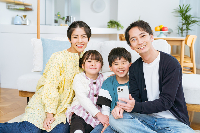 A friendly Japanese family looking at their cell phones.