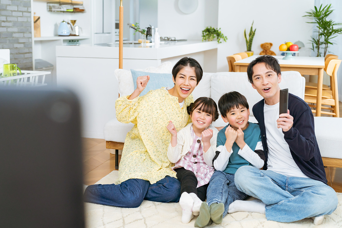 Japanese family of four cheering while watching TV (People)