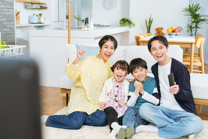Japanese family of four cheering while watching TV (People)