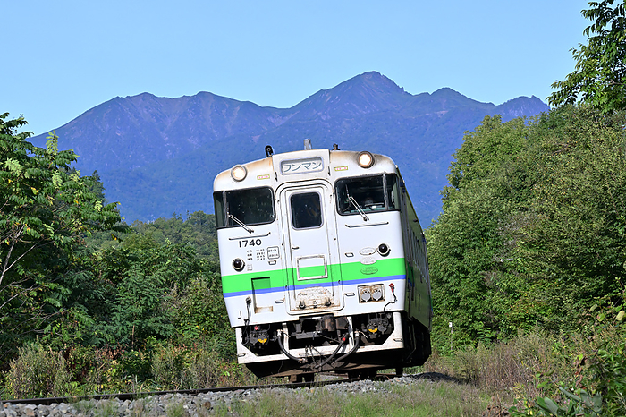 Hokkaido Nemuro Main Line, Type Kiha40 diesel train rounding a curve with Mt. Ashibetsu in the background. Taken at Yamabe Station   Shimokaneyama Station
