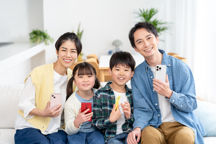 A Japanese family of four sitting on a couch with a cell phone (People)