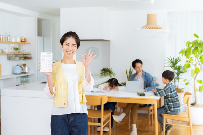 Japanese housewife with calculator in dining room (Female / People)