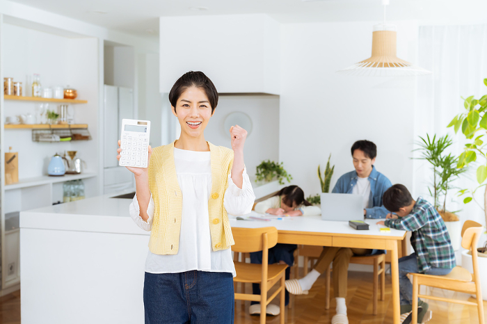 Japanese housewife with calculator in dining room (Female / People)