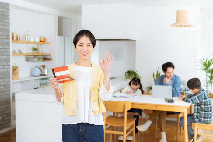 Japanese housewife holding a bankbook in a dining room (Female / People)