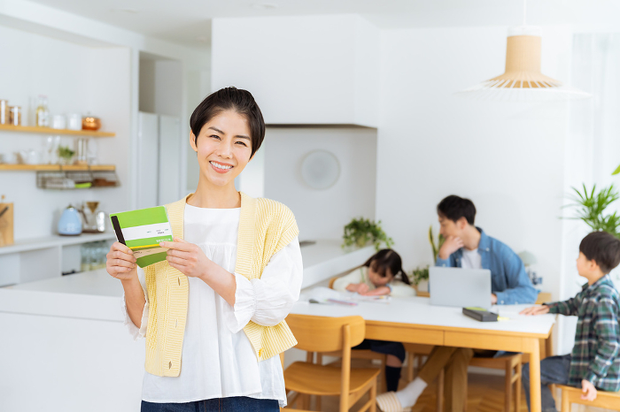 Japanese housewife holding a bankbook in a dining room (Female / People)