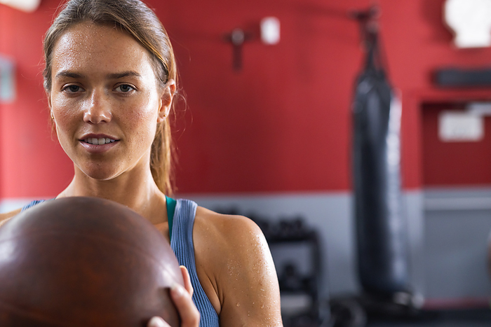 Fit young Caucasian woman at the gym, with copy space. Her focused expression highlights determination during a boxing workout.