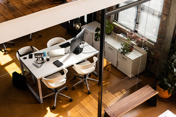 A modern casual business office setup bathed in natural light. The workspace features ergonomic chairs and sleek technology, emphasizing a productive environment.