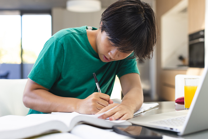Teenage Asian boy studying intently at home. Focused on his homework, he exemplifies dedication to education.