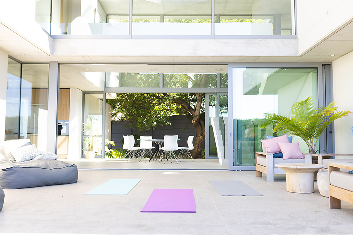 Modern home patio with open sliding doors and yoga mats laid out. The setting suggests a peaceful home environment ideal for relaxation and exercise.