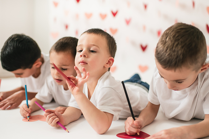 Group of children writing notes on heart shaped cards, by Cavan Images / Julia Maruyama