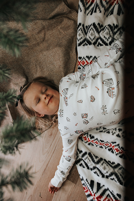 Little girl lays under tree, Christmas serenity, by Cavan Images / Mandi Swandal Photography