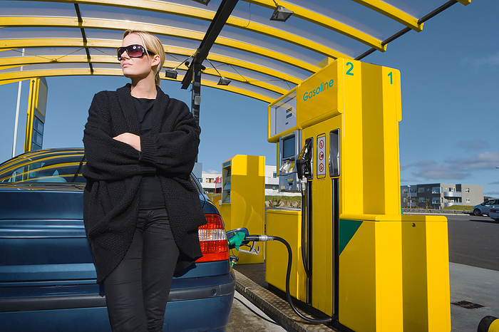 Woman Pumping Gas at Gas Station, by Cavan Images / dund photography