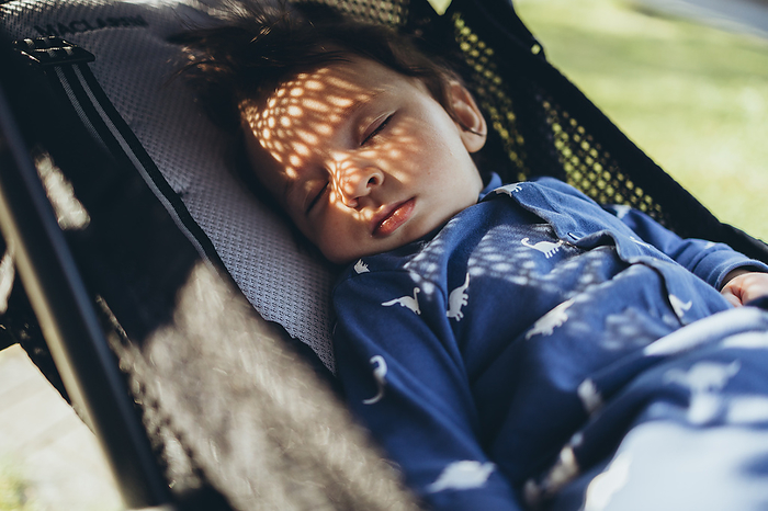 Baby is sleeping on stroller outside, by Cavan Images / Natalia Akulova