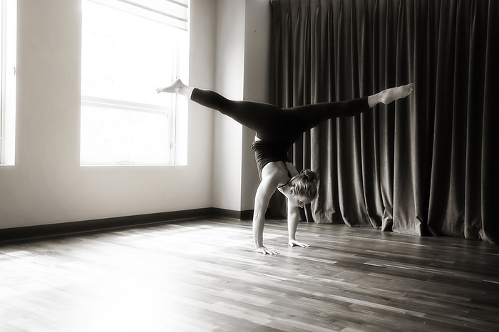 Woman in Handstand Split in front of Curtain, by Cavan Images / Lucie Wicker