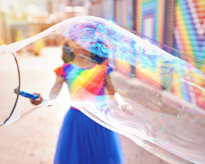 Young Girl Making Huge Bubble in front of a mural in Washington, DC, by Cavan Images / Nikia Paden