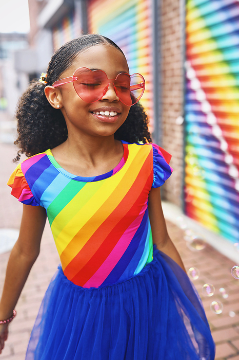 Young Girl smiling with bubbles in front of a mural in Washington, DC, by Cavan Images / Nikia Paden