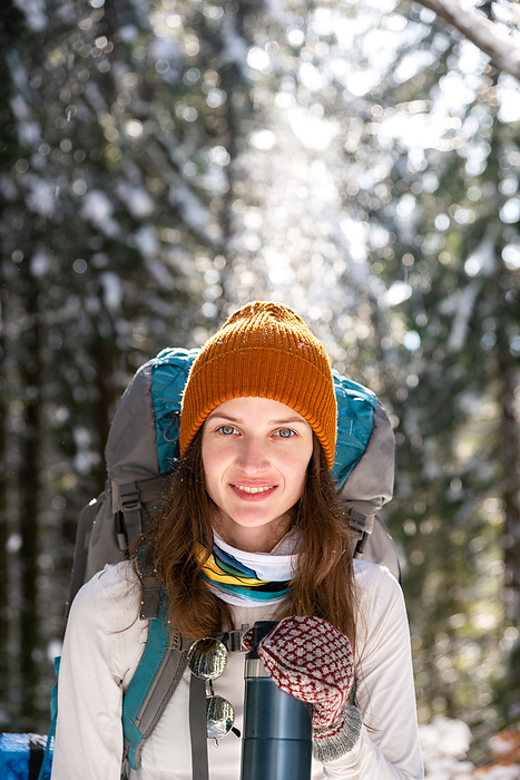 Portrait of Young Woman in Forest Using Insulated Drink Container, by Cavan Images / Artur Abramiv