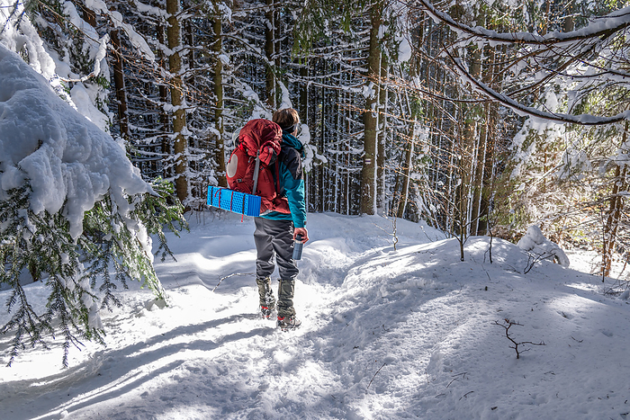 Young Man with Backpack Hiking in the Winter Forest, by Cavan Images / Artur Abramiv