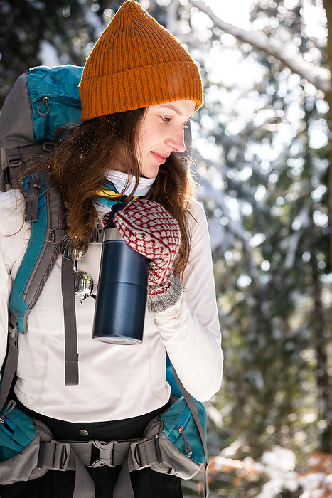 Portrait of Young Woman in Forest Using Insulated Drink Container, by Cavan Images / Artur Abramiv