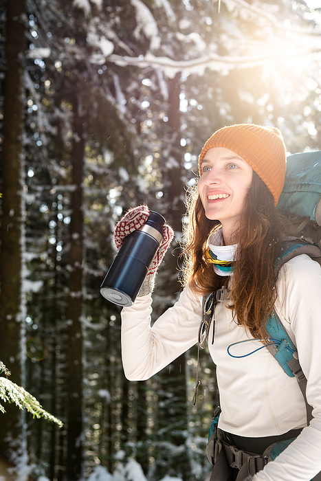 Woman Drinking Tea From Insulated Drink Container During Hiking, by Cavan Images / Artur Abramiv