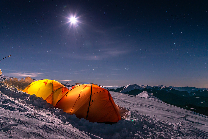 Two Orange Tents On Winter Mountains Against Sky At Night, by Cavan Images / Artur Abramiv