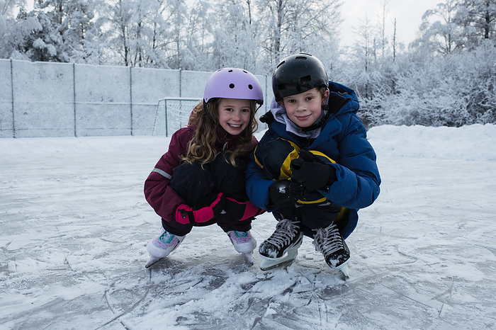 brother and sister ice skating together outside in the snow, by Cavan Images / Rachel Bell