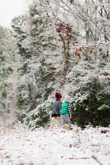 Two little boys exploring the woods in the snow, by Cavan Images / Jamie Sapp