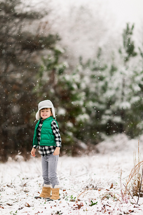 Little boy wearing a plaid shirt playing in the snow, by Cavan Images / Jamie Sapp