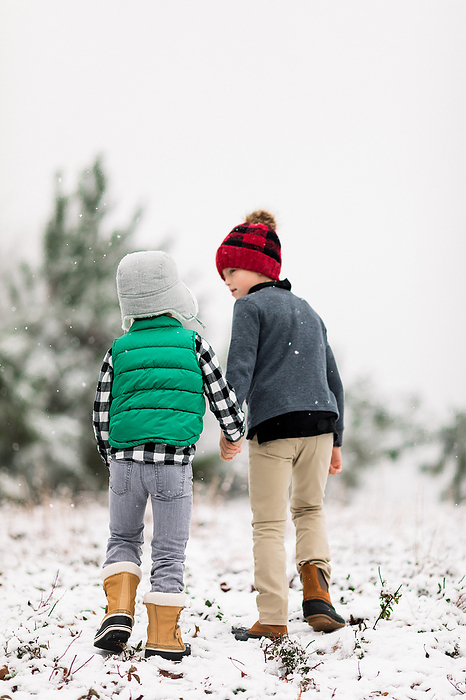 Two boys exploring in their backyard in the snow, by Cavan Images / Jamie Sapp