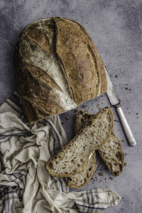 Top view of a country bread loaf, sliced, by Cavan Images / Sara Ghedina