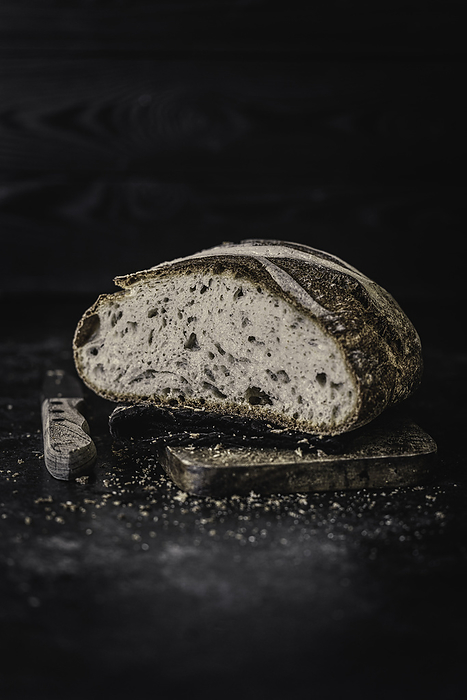 Loaf of Country Bread on Cutting Board with Knife, by Cavan Images / Sara Ghedina