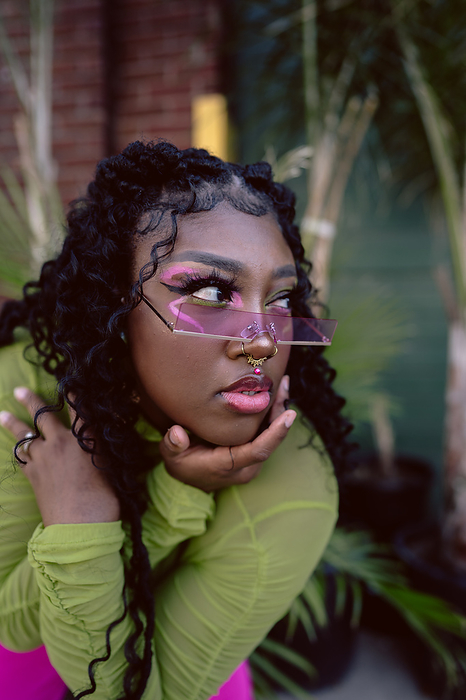 Close-up of young Black woman posing with colorful sunglasses, by Cavan Images / Andrea Guzman