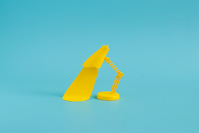Still life yellow desk lamp against a bright blue background, by Cavan Images / Galigrafiya