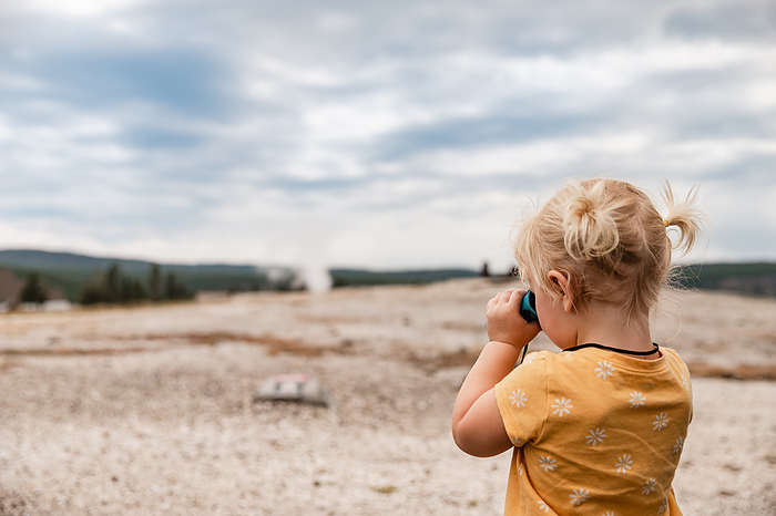 Child looking through binoculars at Yellowstone National Park la, by Cavan Images / Krista Taylor