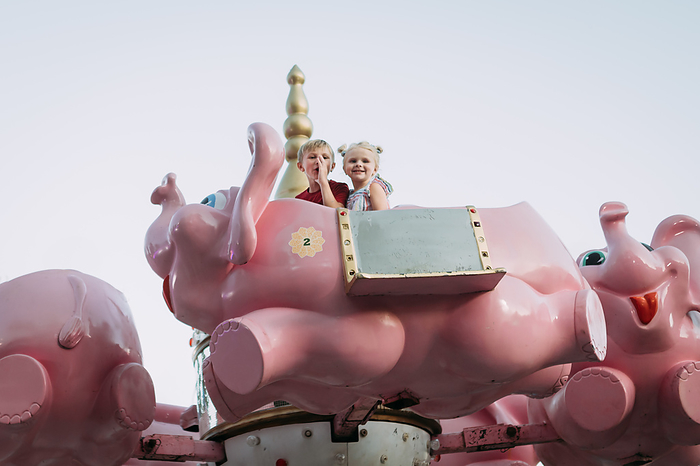 Kids on elephant carnival ride at county fair, by Cavan Images / Krista Taylor