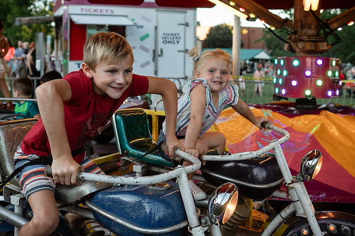 Kids having fun riding carnival ride at summer festival, by Cavan Images / Krista Taylor