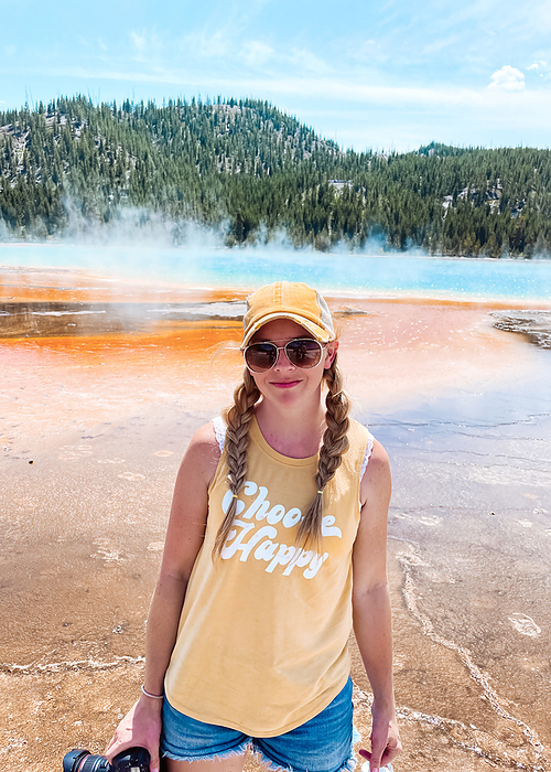 Woman standing in front of Grand Prismatic Spring in Yellowstone, by Cavan Images / Krista Taylor