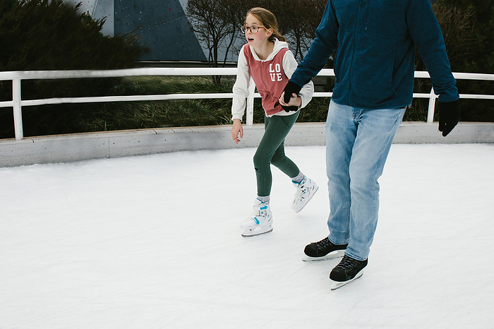 Daughter holds Dads hand while they ice skate together, by Cavan Images / Anna Rasmussen Photographs