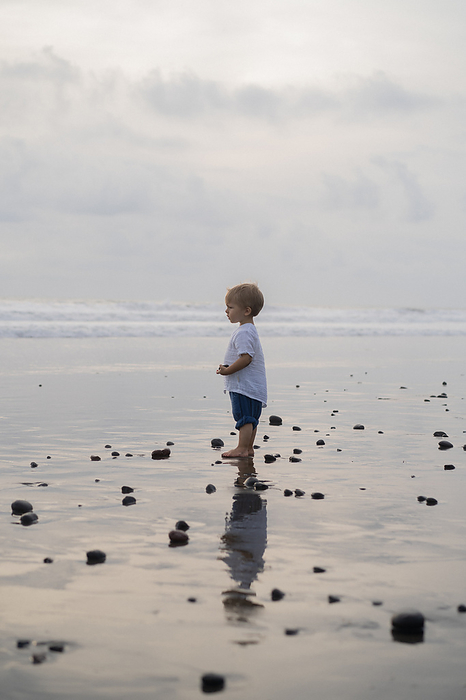 Little boy child near the ocean on the beach, Bali., by Cavan Images / Yuliya Kirayonak