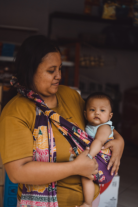 Balinese woman holding a small baby in her arms, motherhood portrait., by Cavan Images / Yuliya Kirayonak