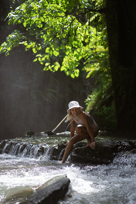 Woman traveler on an adventure at a tropical waterfall, Bali., by Cavan Images / Yuliya Kirayonak