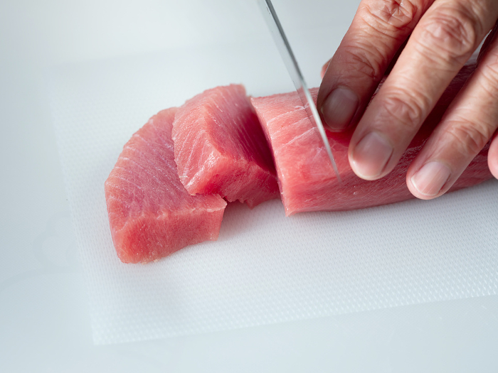 Male hand cutting the medium fatty tuna