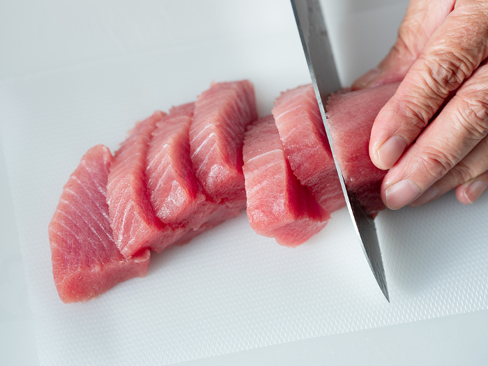Male hand cutting the medium fatty tuna
